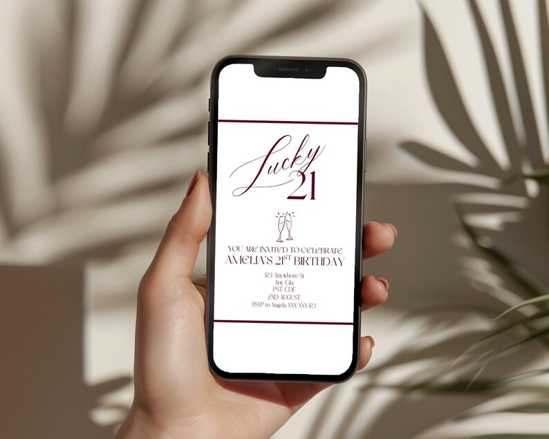May include: A smartphone displays a digital invitation for a "Lucky 21" birthday celebration. The invitation features elegant burgundy text on a white background, including the name "Amelia's" and event details. The phone is held in a person's hand.