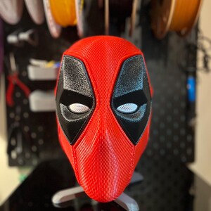 Peut inclure: Un masque Deadpool imprimé en 3D rouge et noir avec des trous pour les yeux blancs.