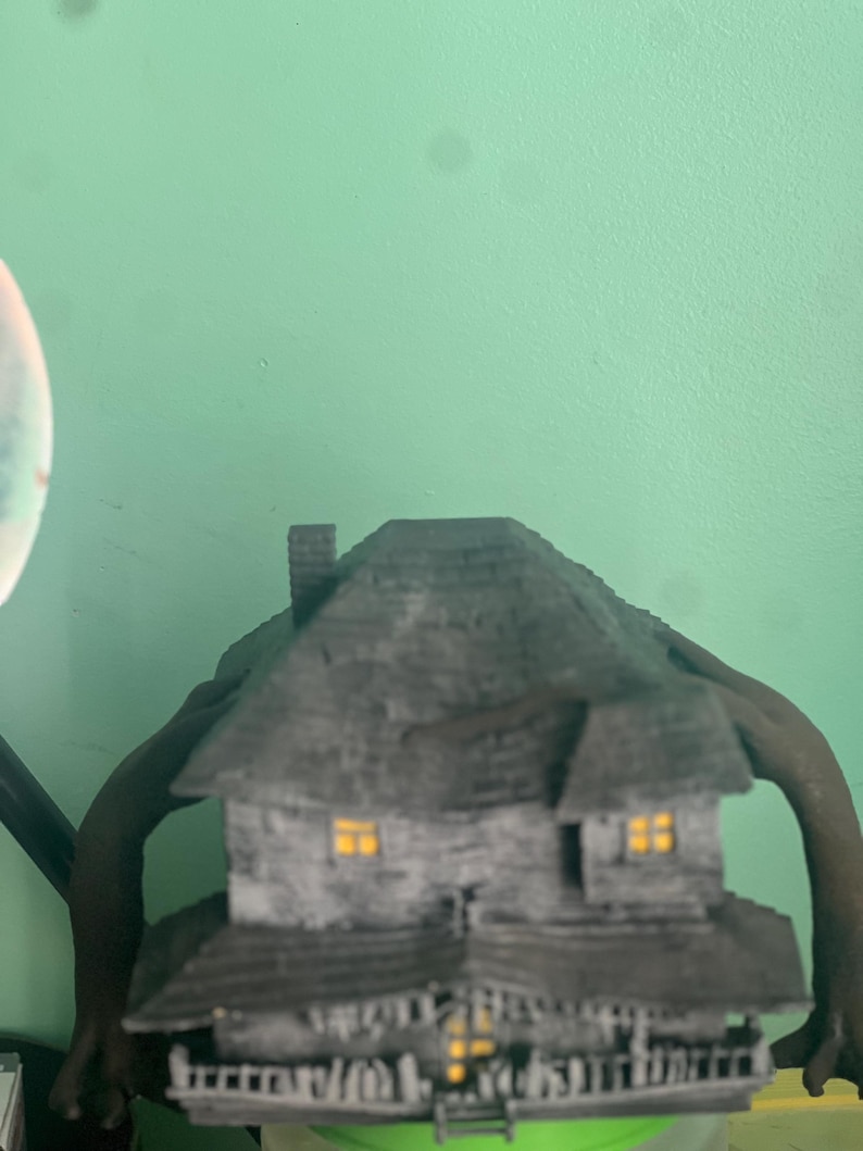 May include: A black and gray model of a house with windows and a porch. The house is sitting on a green surface.