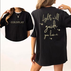 May include: Black t-shirt with the text "COLDPLAY" on the front and "Lights will guide you home" with stars on the back.