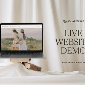 May include: A laptop computer displaying a website with the text "Amazing Stories Tenderly Told" on the screen. The laptop is on a wooden platform and a white ball is in the foreground. The background is a white fabric backdrop with the text "SQUARESPACE LIVE WEBSITE DEMO LINK IN DESCRIPTION" in black.