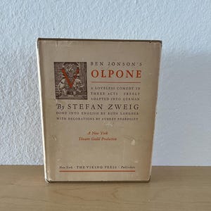 May include: A vintage book titled "OLPONE" by Ben Jonson, with text in English and German. The cover is beige with black and red text, and a small illustration. Published by The Viking Press in New York.