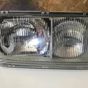 A clear headlight of a vehicle, with a reflective surface that allows light to pass through.