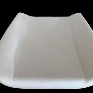 A white, rectangular object resembling a changing pad or pad for a baby.