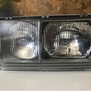 a clear headlight of a vehicle, with a metallic finish and a reflective surface.