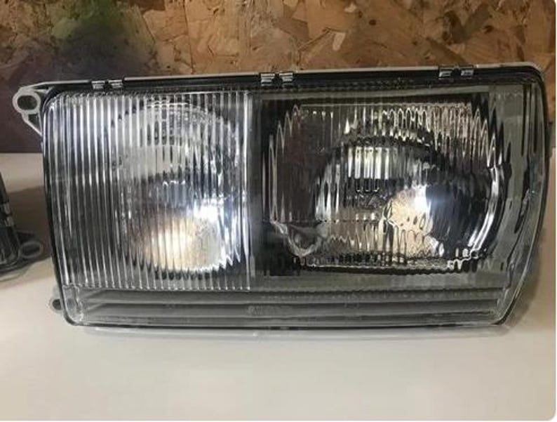 a clear headlight of a vehicle, with a metallic finish and a reflective surface.