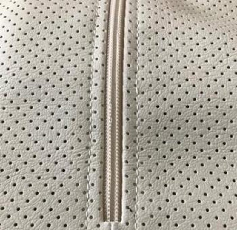 a close-up view of a white fabric with a perforated pattern, featuring a zipper running vertically down the center.