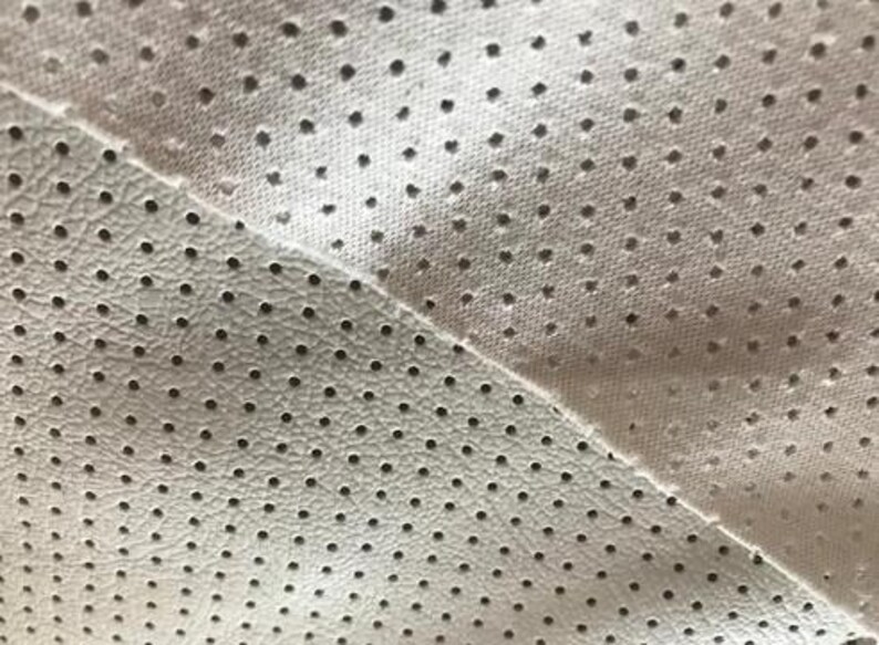 a close-up view of a fabric with a perforated pattern, featuring numerous small holes or dots.