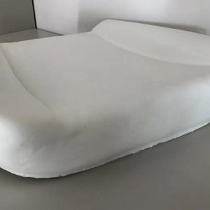 A white, rectangular object resembling a pillow or cushion is shown in the image.