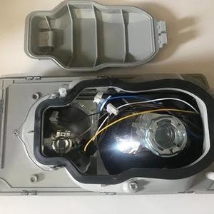 the interior of a vehicle, specifically the front headlight assembly, with the headlight removed and the headlight housing visible.