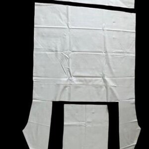 a white fabric with several cut-out pieces, likely for a sewing or crafting project.