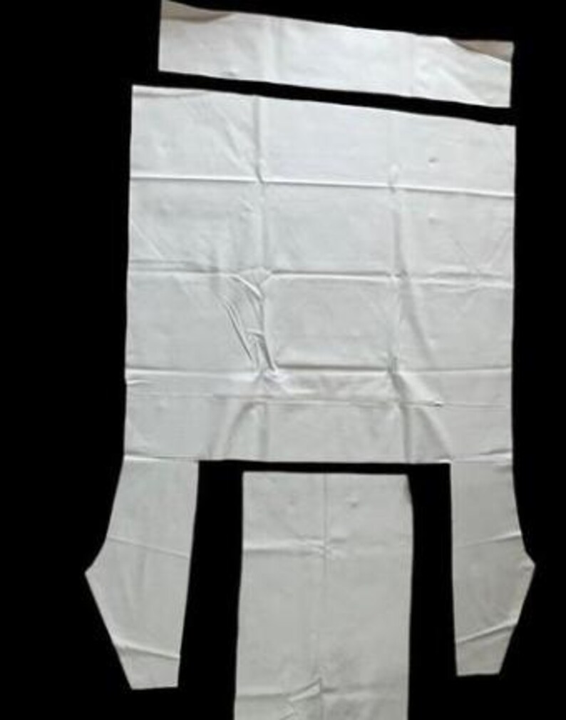 a white fabric with several cut-out pieces, likely for a sewing or crafting project.