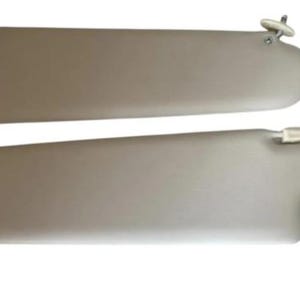 May include: Two beige car sun visors, arranged one above the other. Each visor has a rectangular shape with a curved edge and a mounting mechanism. The background is white.