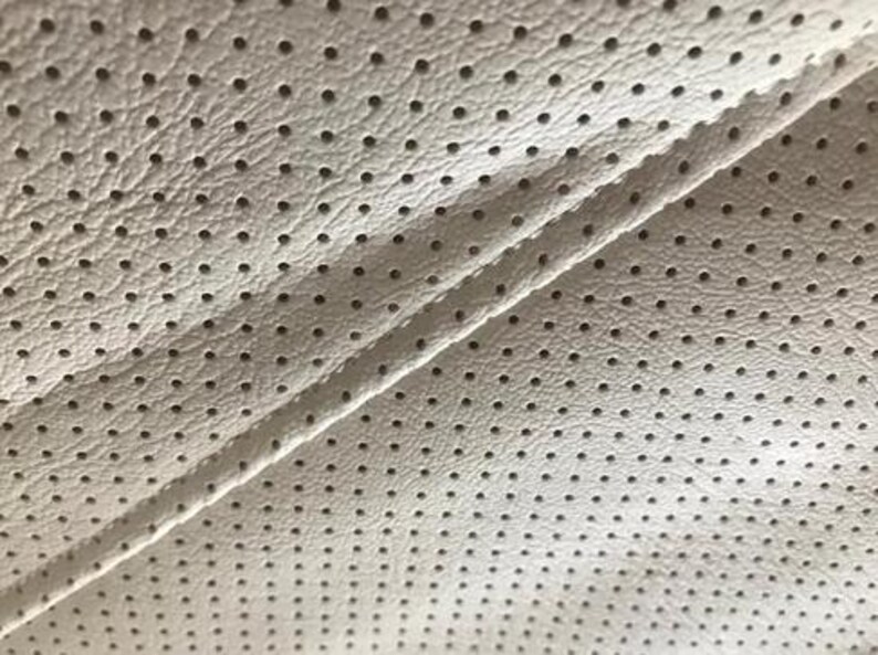 a close-up view of a white fabric with a perforated pattern, featuring numerous small holes or dots arranged in a grid-like pattern.