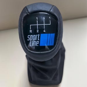 May include: A black car gear stick with the text "Sport Line" and a gear shift pattern. The pattern includes the numbers 1, 2, 3, 4, 5, and R. A blue bar graphic is also present.