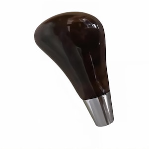 Może przedstawiać: Ciemnobrązowa, błyszcząca drewniana gałka zmiany biegów z chromowaną podstawą. Gałka zmiany biegów ma gładką, ergonomiczną konstrukcję i prawdopodobnie służy do zmiany biegów w pojeździe.