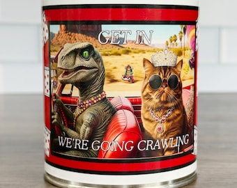 May include: A metal can with a red and white design featuring a dinosaur and a cat in a car. The dinosaur is wearing a necklace and the cat is wearing sunglasses and a crown. The text on the can reads "GET IN" and "WE'RE GOING CRAWLING."