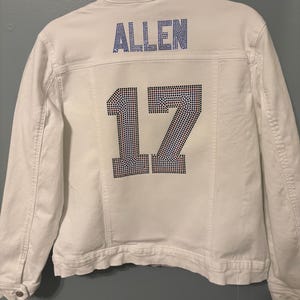 Puede incluir: Chaqueta vaquera blanca con el nombre "ALLEN" y el número "17" en pedrería en la parte posterior.