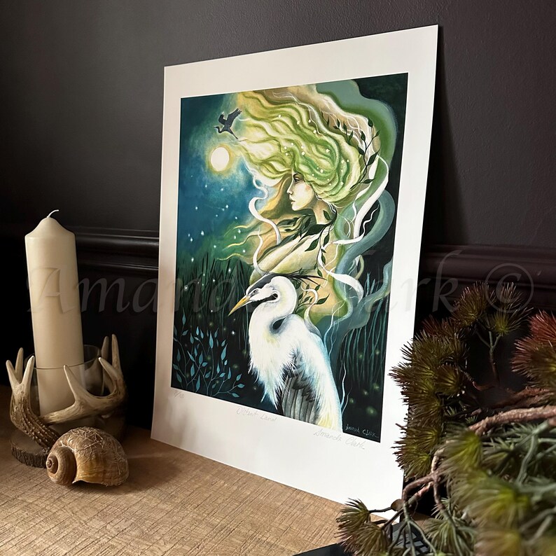 May include: A green and blue illustration of a woman with long flowing hair and a white heron. The woman is surrounded by green foliage and the moon is visible in the background.