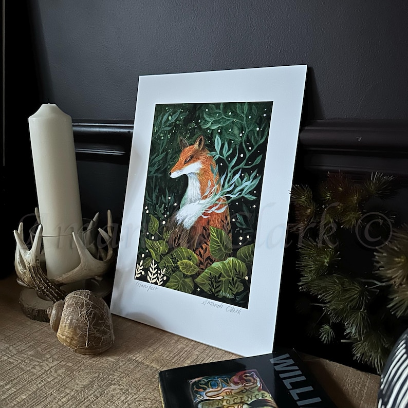 May include: A print of a fox in a forest setting. The fox is orange and white with a black nose and eyes. The background is dark green with white dots and green leaves. The print is signed "Amanda Clark".