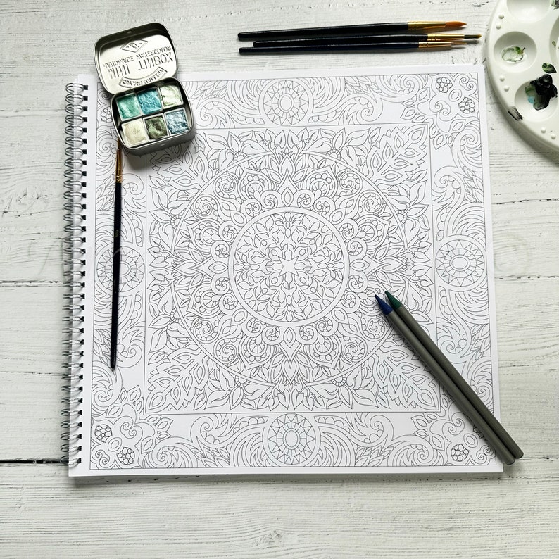 Puede incluir: Una p&aacute;gina de libro para colorear de mandala en blanco y negro con un dise&ntilde;o detallado. La p&aacute;gina est&aacute; abierta sobre una mesa blanca con un juego de acuarelas y l&aacute;pices.