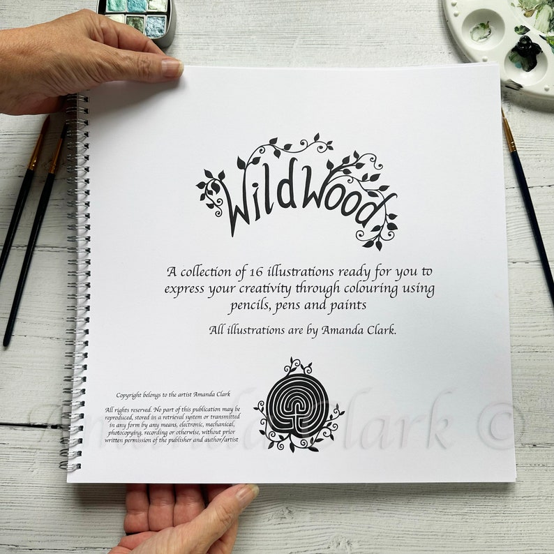 Puede incluir: Un libro para colorear en blanco y negro titulado "Wild Wood" con una colecci&oacute;n de 16 ilustraciones. La portada presenta un &aacute;rbol estilizado con hojas y el t&iacute;tulo en una fuente decorativa. El texto en la portada dice "Una colecci&oacute;n de 16 ilustraciones listas para que expreses tu creatividad coloreando con l&aacute;pices, bol&iacute;grafos y pinturas. Todas las ilustraciones son de Amanda Clark."