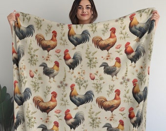May include: A cream-coloured throw blanket featuring a repeating pattern of colourful roosters and floral accents. The roosters are depicted in a vintage style with red, orange, and yellow plumage.