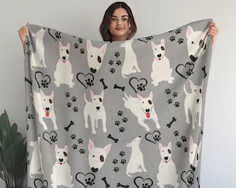 Puede incluir: Una manta de franela gris con un patrón de perro bull terrier blanco. La manta presenta huellas de patas negras, corazones y huesos.