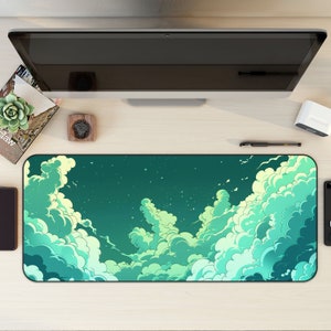 May include: A green and blue mousepad with a design of clouds and stars. The mousepad is on a wooden desk with a computer monitor, a book, and a small plant.