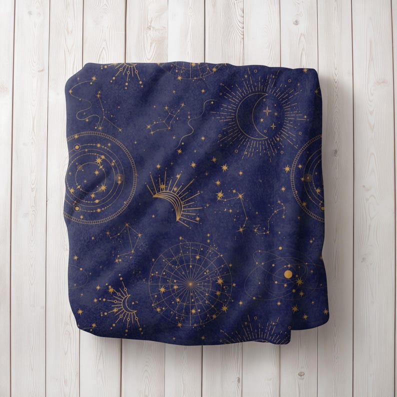 May include: A navy blue throw blanket with a gold celestial pattern. The pattern features stars, constellations, moons, and suns.