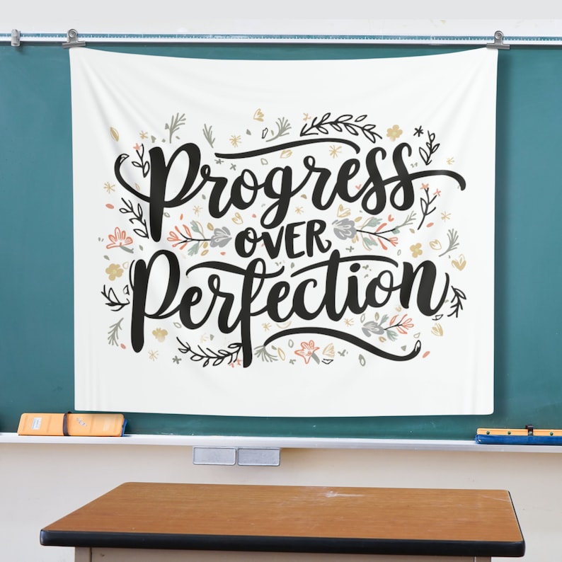 K&ouml;nnte beinhalten: Wei&szlig;e Wandbeh&auml;nge mit dem Text "Progress over Perfection" in schwarzer Schrift. Der Text ist von einem floralen Design in Rosa-, Blau- und Gelbt&ouml;nen umgeben.