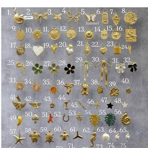 May include: A collection of gold-toned charms with various designs, including butterflies, hearts, stars, and bows. Some charms have enamel details. The image includes charms with the text "Enamel" and "11:11".