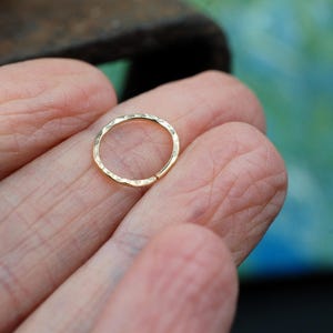 May include: A gold hammered ring, a type of jewellery often used as a nose ring or ear ring.