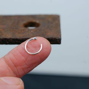 May include: A small silver nose ring with a ball on the end.