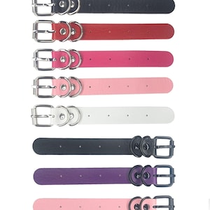 May include: Eight leather collars in different colors, including black, red, pink, light pink, white, purple, and two more white collars. Each collar has a silver buckle and two silver rings.