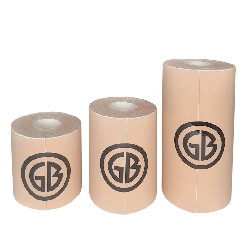 K&ouml;nnte beinhalten: Drei Rollen beigefarbenes Klebeband mit einem schwarzen Kreislogo, auf dem "GB" steht.