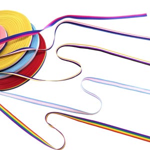 May include: A stack of colorful ribbon spools, including yellow, red, blue, pink, and purple, with rainbow ribbon extending from the stack.