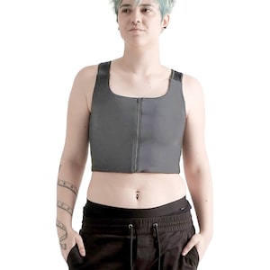 Puede incluir: Una persona con un top de compresión gris con cremallera y pantalones negros.