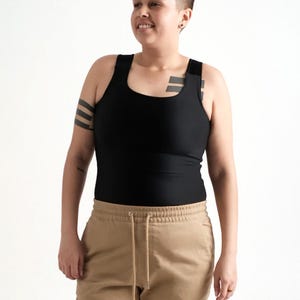 Peut inclure: Un débardeur noir sans manches avec de larges bretelles et une encolure dégagée, associé à un pantalon cargo beige avec une taille à cordon et des poches latérales. Le débardeur est ajusté, tandis que le pantalon a une coupe décontractée.