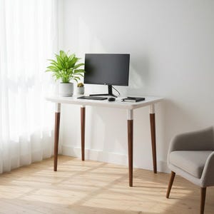 Könnte beinhalten: Ein weißer Schreibtisch mit dunkelbraunen Beinen und einem Computermonitor. Eine Topfpflanze und eine kleine Sukkulente stehen auf dem Schreibtisch. Eine Tastatur, eine Maus und ein Notizbuch befinden sich ebenfalls auf dem Schreibtisch. Rechts vom Schreibtisch steht ein grauer Sessel.