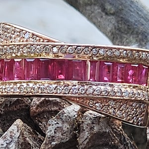 Könnte beinhalten: Ein goldener Ring mit einer Reihe von rosafarbenen Rubin-Steinen und einem Diamantenband.