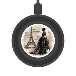 May include: Black wireless charger with a circular design. The center features an illustration of a woman in a black gown with pink floral accents, the Eiffel Tower, and the text "A diva is a queen who rules with grace and authority."