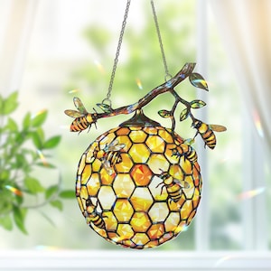 May include: A hanging decorative light fixture with a honeycomb design. The globe is yellow and orange with a hexagonal pattern. Several bee figurines are attached to the fixture and a branch. The fixture hangs from a chain.