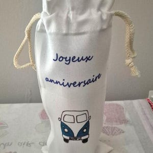 Peut inclure: Sac à bouteille de vin en toile blanche avec fermeture à cordon et une illustration bleue et blanche d'une camionnette vintage. Le sac porte les mots "Joyeux anniversaire" en écriture bleue.