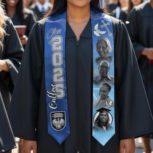 May include: A group of graduates in black gowns and mortarboards. A woman in the centre smiles, wearing a blue sash with the text "Class of 2023" and photos. The background shows a university building and other graduates.