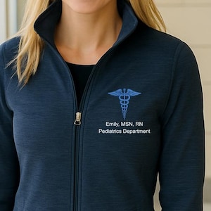 May include: Navy blue zip-up jacket with a medical caduceus emblem and the text "Emily, MSN, RN Pediatrics Department." The jacket has a high collar and two front pockets. The jacket is made of a soft, textured material.