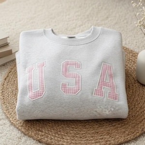 Moletom com capuz, camiseta e blusa de moletom com apliques de letras e iniciais da faculdade bordadas em patchwork.