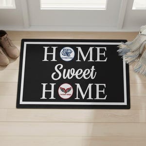 May include: Black rectangular doormat with the words "HOME Sweet HOME" in white. The mat has a white border and two team logos. A pair of tan boots and a potted plant are visible to the left. A basket with a scarf is to the right.