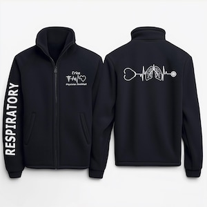 May include: Black fleece jacket with a zipper closure. The left sleeve has the word "RESPIRATORY" printed vertically in white. The right side of the jacket has a white graphic of a stethoscope, heart, lungs, and EKG line. The left side of the jacket has the text "Erica Physician Assistant" printed in white.