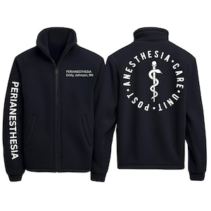 Puede incluir: Chaqueta polar negra con cremallera completa y cuello alto. La manga izquierda tiene la palabra "PERIANESTHESIA" impresa verticalmente en blanco. El frente tiene el texto "PERIANESTHESIA Emily Johnson, RN". La parte trasera presenta un símbolo médico blanco y las palabras "POST ANESTHESIA CARE UNIT".
